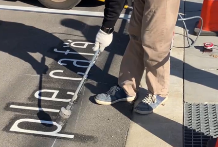 アスファルトにカフェのロゴを貼付する社員